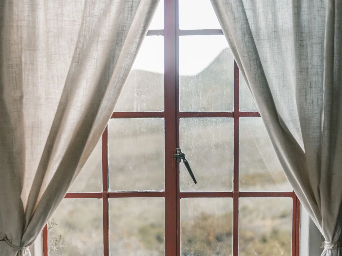 A bedroom with layered blackout curtains and a closed room-darkening shade