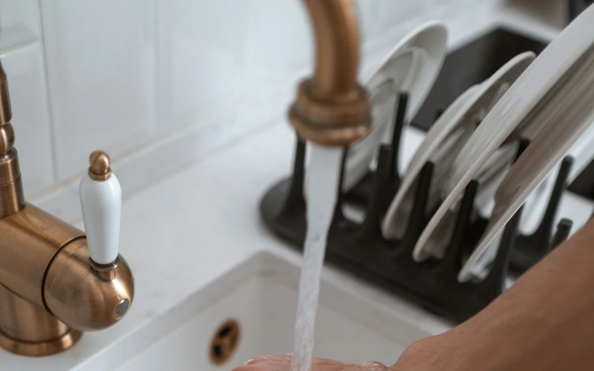 A person unloading dishes from a dishwasher in a bright kitchen