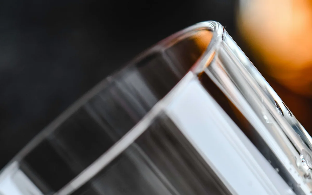 Ice cubes being scooped into a glass from a compact countertop appliance