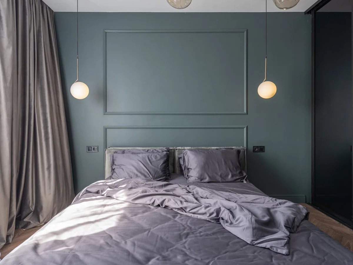 A bright guest bedroom with a made bed, luggage bench, and built-in storage