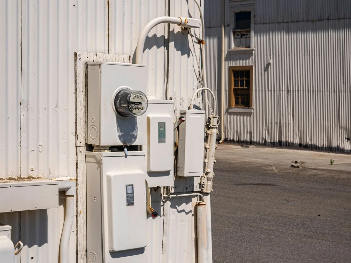 An electrician inspecting a whole-home surge protector beside an electrical panel